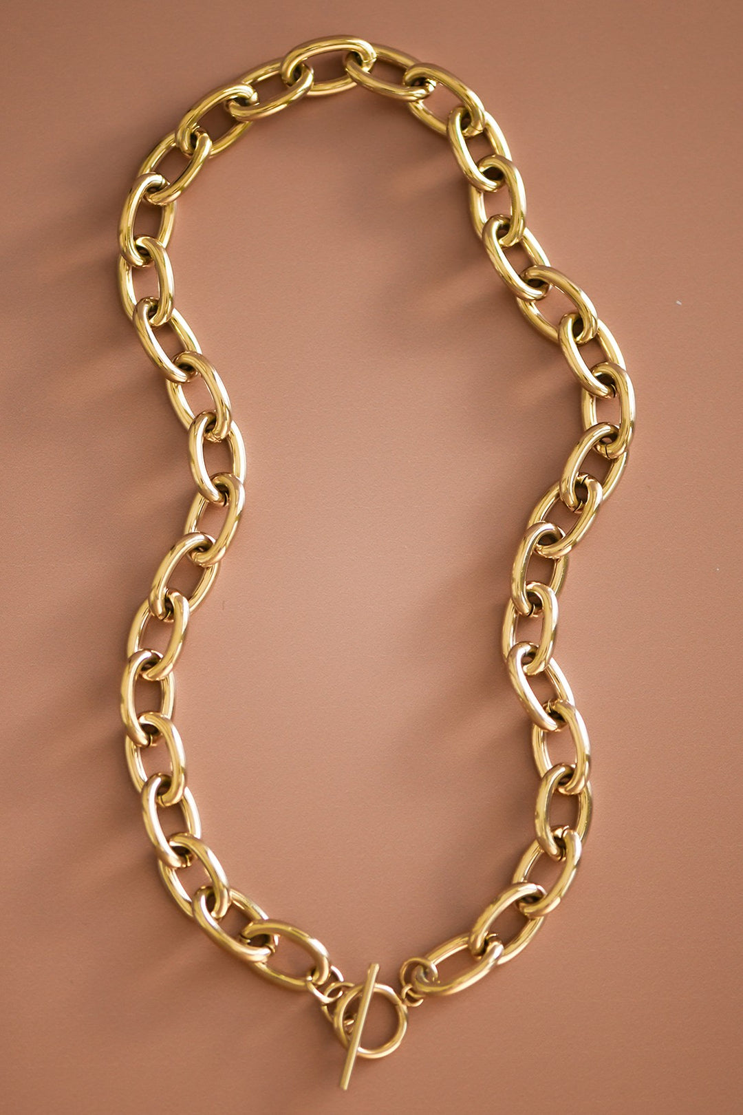 Gold chain necklace on a brown background