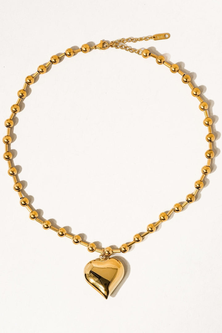 Gold necklace with a heart-shaped pendant on a white background