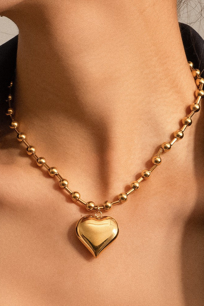 Gold heart-shaped pendant necklace on a person's neck