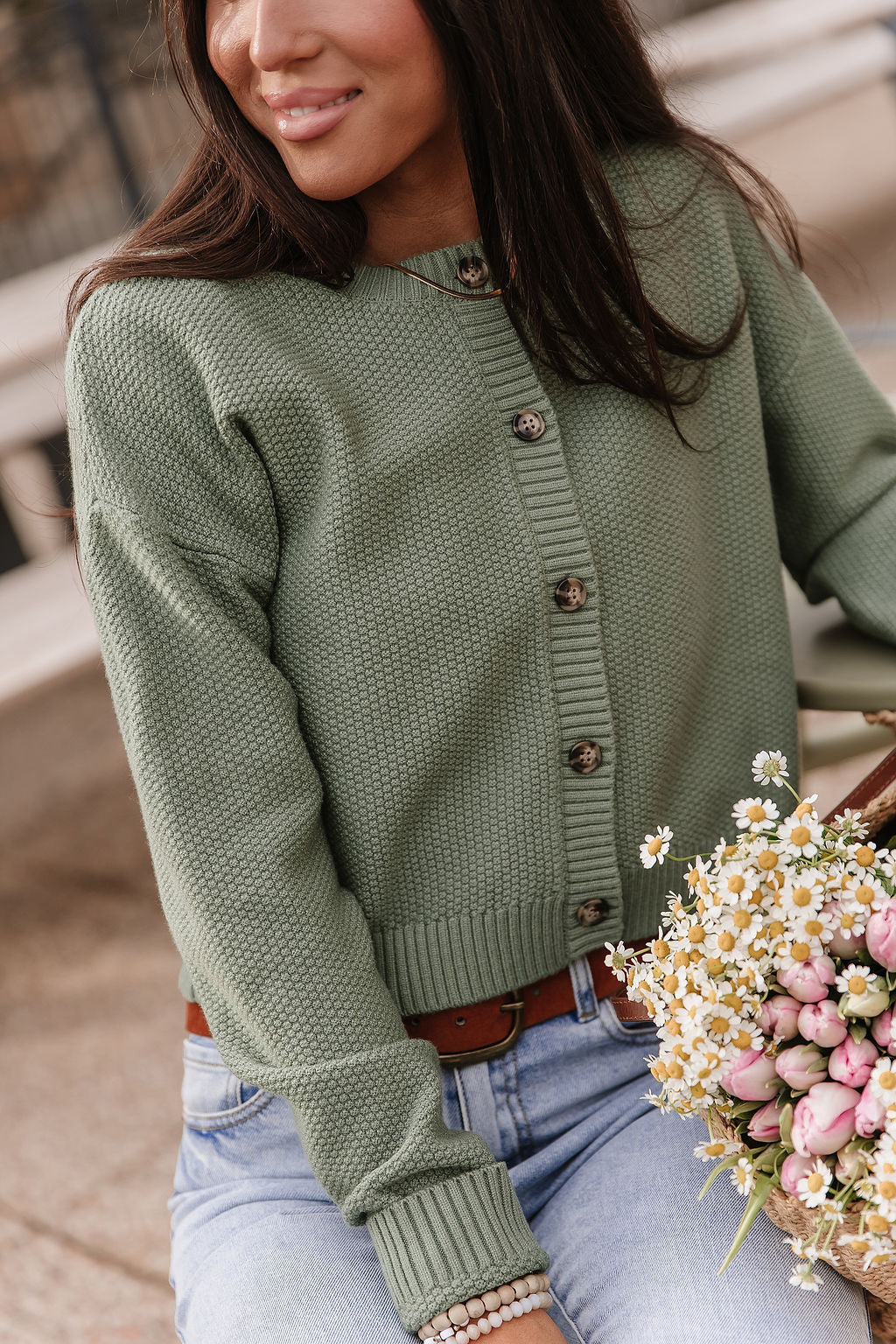 Woman wearing soft green cloud knit cardigan in fern color with relaxed fit layered over casual outfit