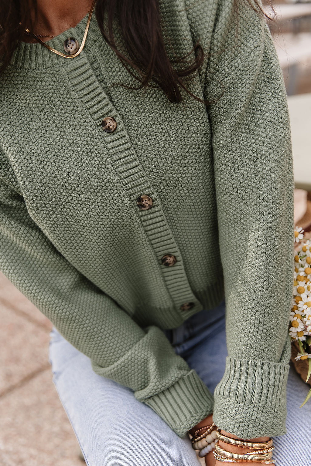Woman wearing soft green cloud knit cardigan in fern color with relaxed fit layered over casual outfit