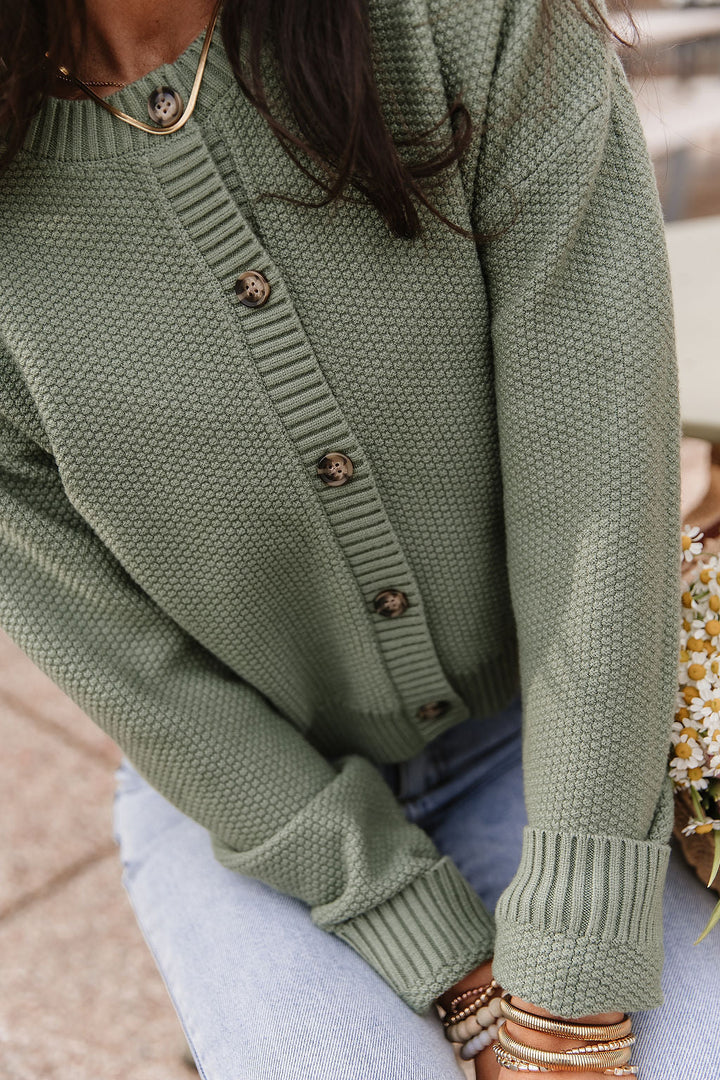 Woman wearing soft green cloud knit cardigan in fern color with relaxed fit layered over casual outfit