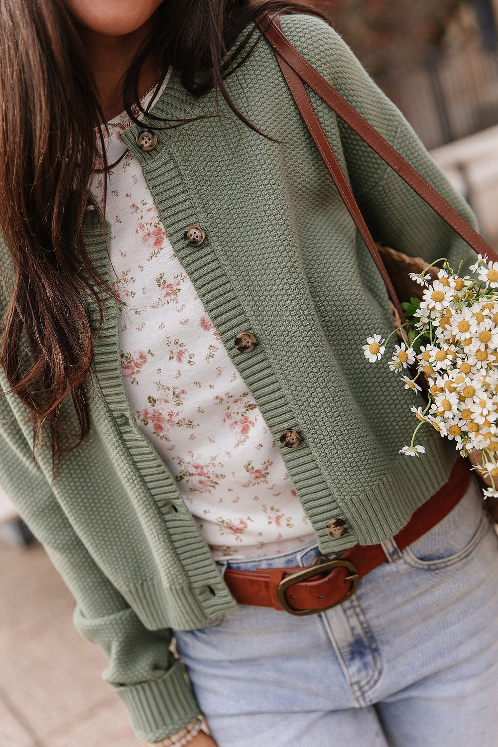Woman wearing soft green cloud knit cardigan in fern color with relaxed fit layered over casual outfit