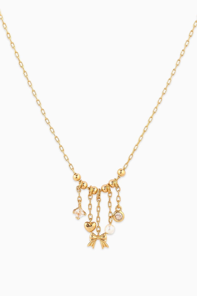 Gold necklace with heart and bow charms on a white background