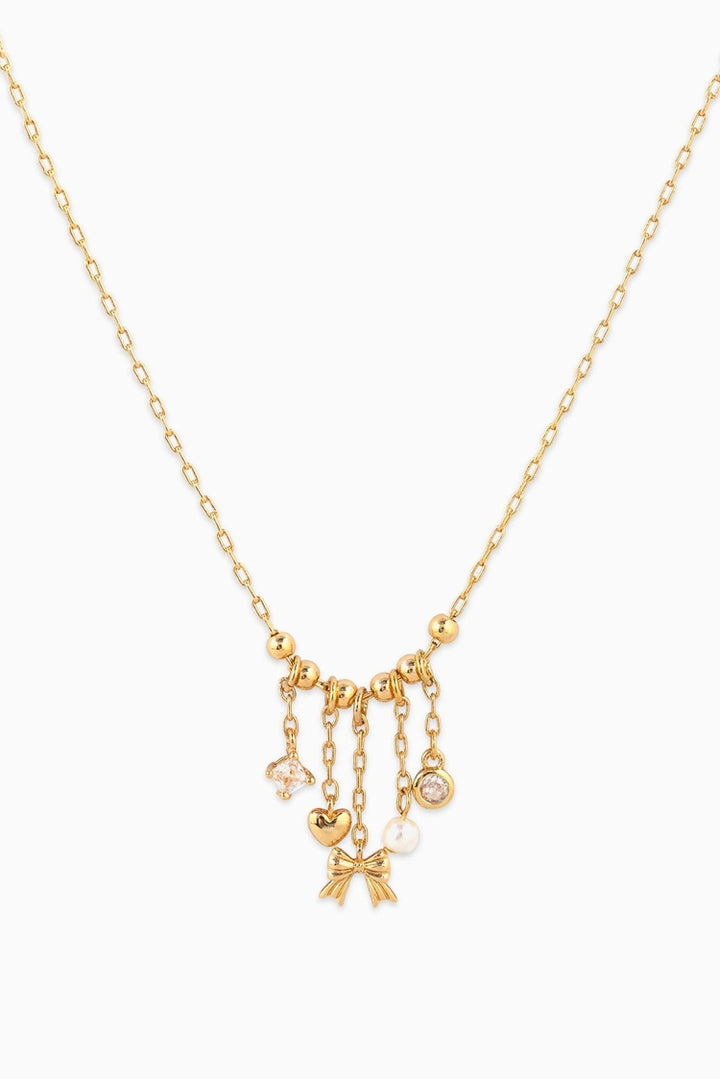 Gold necklace with heart and bow charms on a white background