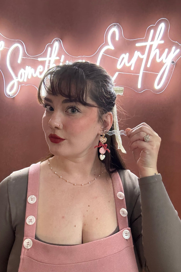 Woman wearing pink overalls with a neon sign in the background