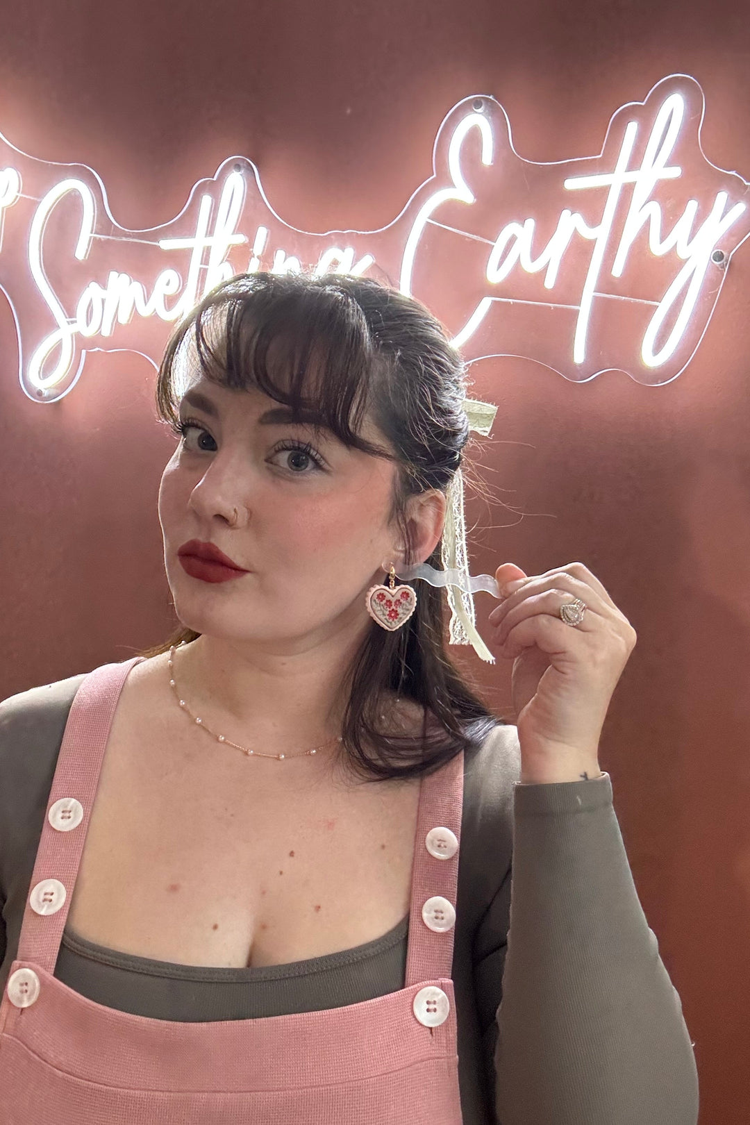 Woman wearing pink overalls with a neon sign in the background
