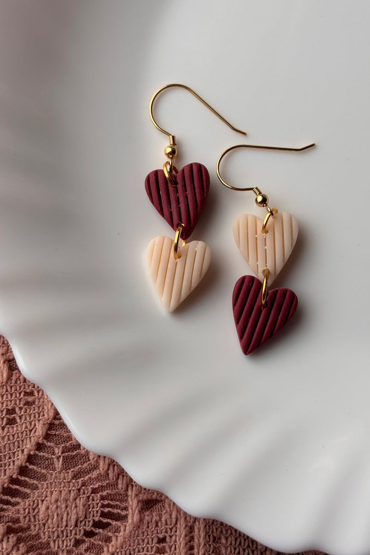 Heart-shaped earrings on a white plate with a textured surface