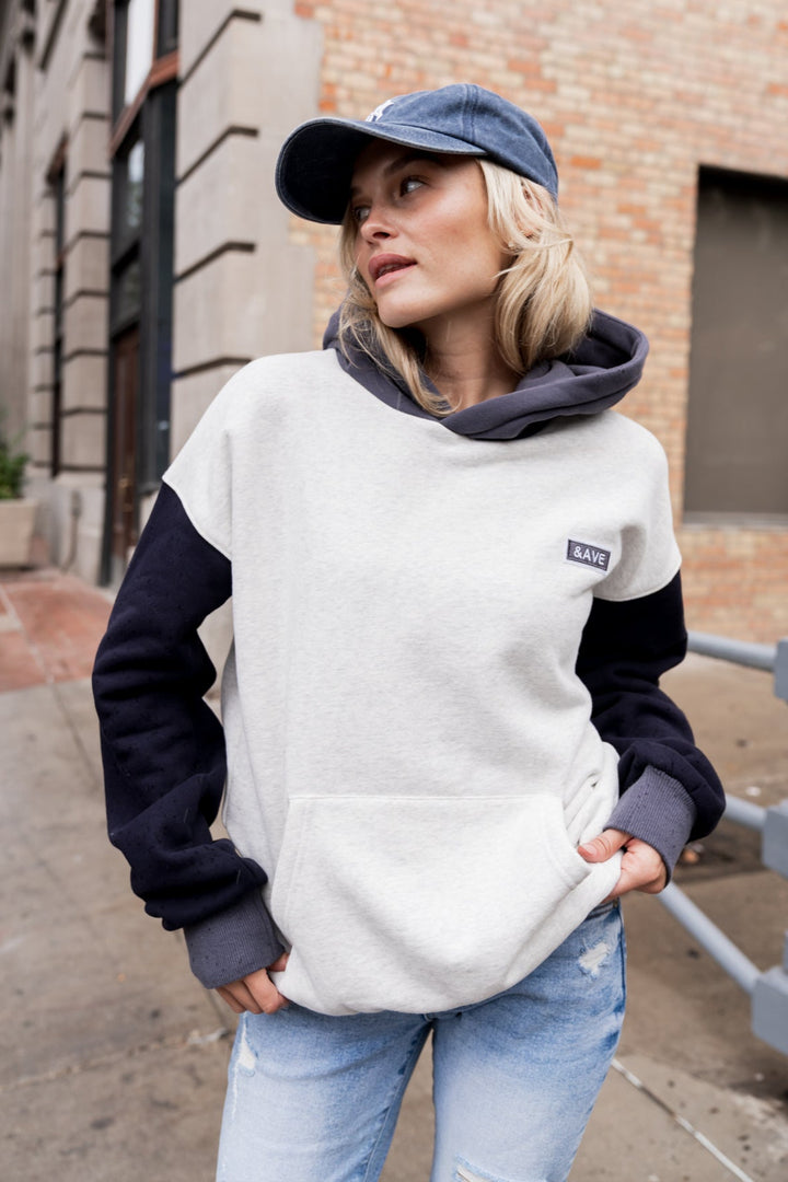 Woman wearing a white and navy hoodie with a Patagonia logo, standing on a city street.