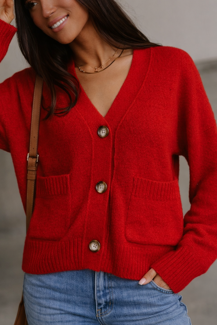 Person wearing a red cardigan with a neutral background