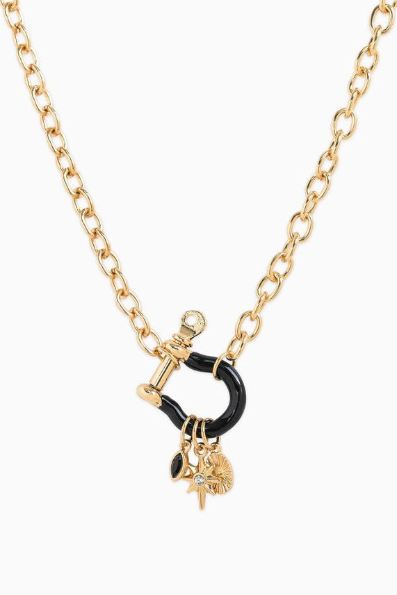 Necklace with gold chain, black pendant, and small charm on a white background